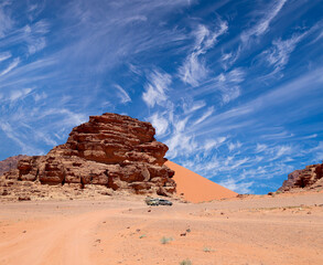 Wadi Rum Desert also known as The Valley of the Moon (against the sky with clouds)-- is a valley cut into the sandstone and granite rock in southern Jordan 60 km to the east of Aqaba