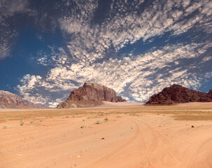 Wadi Rum Desert also known as The Valley of the Moon (against the sky with clouds)-- is a valley cut into the sandstone and granite rock in southern Jordan 60 km to the east of Aqaba