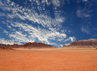 Wadi Rum Desert also known as The Valley of the Moon (against the sky with clouds)-- is a valley cut into the sandstone and granite rock in southern Jordan 60 km to the east of Aqaba