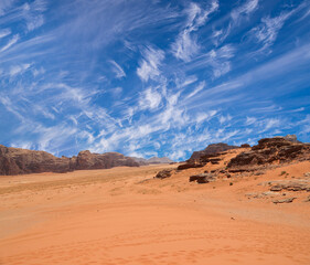 Wadi Rum Desert also known as The Valley of the Moon (against the sky with clouds)-- is a valley cut into the sandstone and granite rock in southern Jordan 60 km to the east of Aqaba