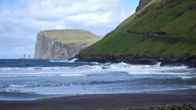 Risin and Kellingin sea rocks viewed from Tjornuvik bay, with waves crashing on the shore of Streymoy, Faroe Islands.