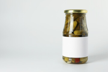 Pickled cucumbers in jar on light background. Space for text