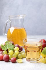 Ripe grapes and tasty juice on grey table