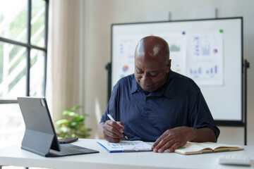 Happy African American businessman working with documents, preparing reports or marketing analysis, financial calculations. Working on a laptop computer online Contacting customers in a modern office