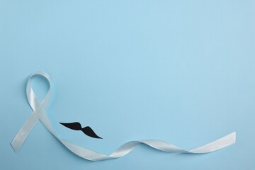 Light blue ribbon and fake mustache on color background, top view with space for text. Prostate...