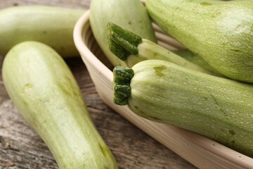 Raw green zucchinis on wooden table, closeup