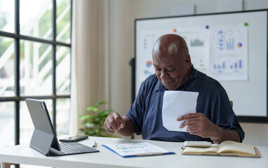 African American adult businessman upset. Depression. Senior man working in office with paperwork. Dissatisfied with the financial results of an investment malfunction Office syndrome concept.