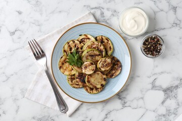 Tasty grilled courgette slices with parsley served on white marble table, flat lay
