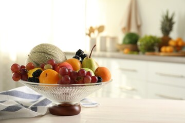 Glass vase with different fruits and berries on white table indoors. Space for text