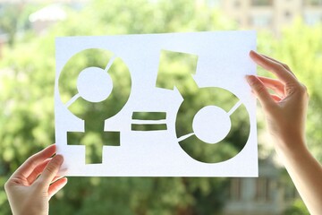 Gender equality concept. Woman holding paper with female and male symbols outdoors, closeup