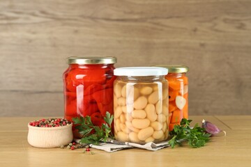 Different pickled products in jars and spices on wooden table