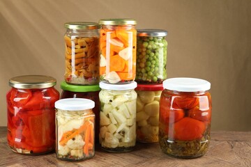 Different pickled products in jars on wooden table