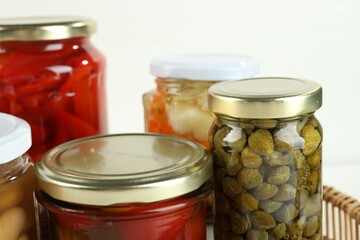 Different pickled products in jars on white background, closeup