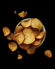 cassava chips, golden and crunchy, elegantly placed on a black background.