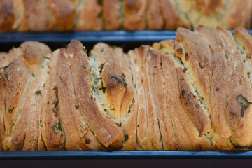 Two loaves of freshly baked pull apart bread with garlic and rosemary in metal pans