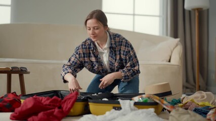 Traveling and resting in summer, portrait of young woman packaging suitcase. Smiling positive girl preparing to summer vacation, putting clothes into bag, remove to other house, happiness and joy