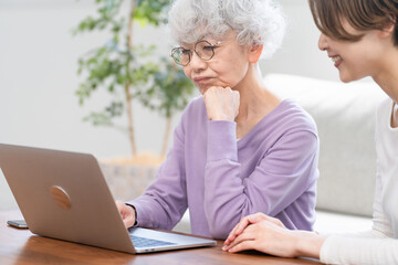 若い女性にパソコン操作を習うシニア女性