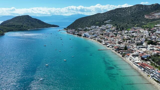 Aerial drone video of famous seaside village small port and long sandy beach of Tolo with hotels and resorts built by the sea, Argolida, Peloponnese, Greece