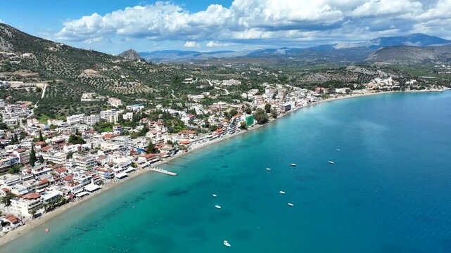 Aerial drone video of famous seaside village small port and long sandy beach of Tolo with hotels and resorts built by the sea, Argolida, Peloponnese, Greece