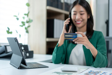 A woman is talking on her cell phone while holding a credit card