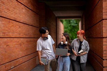 Three young people are walking down a brick hallway, each carrying a book