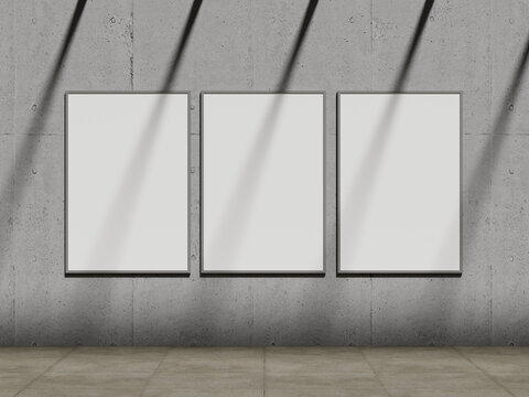 Three blank vertical poster mockups on concrete wall with window shadows