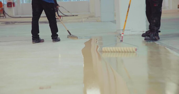 The workers skillfully apply a coat of epoxy resin onto the freshly laid floor, ensuring a seamless and durable finish