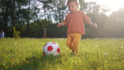 kid are playing ball on the court. happy family kid dream concept. Toddler playing ball park. child son in an orange T-shirt playing ball lifestyle on green grass in the park in summer