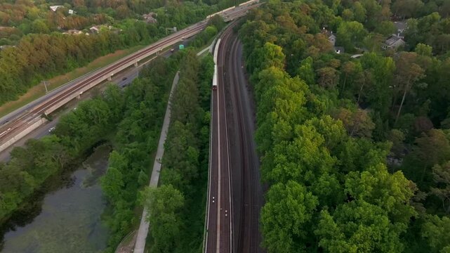 Drone shot of Atlanta metro rail crossing through natural park trails of Buckhead neighbourhood, Georgia State Route 400, T Harvey Mathis Parkway