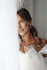 The charming brunette lady in a white dress poses gracefully in a sleek, minimalist white setting. Her captivating smile and radiant aura highlight her natural beauty