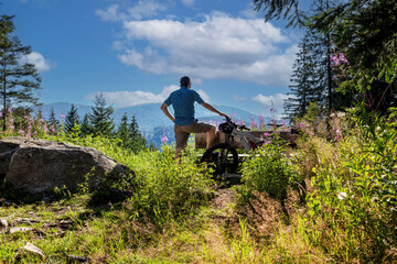Radfahrer macht Pause auf einer Bank mit Blick auf den Feldberg im Schwarzwald