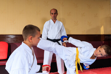 Athlete in blue pads throws a roundhouse kick at an athlete in red pads