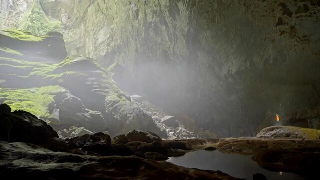 A panning shot capturing a person navigating the immense scale of Donline 1 within the Hang Son Doong cave, Vietnam ,- 4K Prores 422