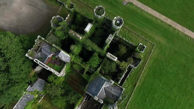 Castle Saunderson, County Cavan, Ireland, September 2022. Drone in Bird's Eye View rotates above the ruined Castle featuring towers stairs and overgrown interior filled with wild Ivy greenery.