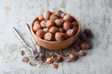 Wooden plate full of hazelnuts with silver nutcracker. Food photography