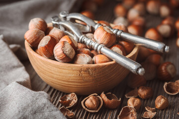 Vintage silver nutcracker on wooden plate full of open hazelnuts. Food photography