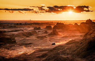 The view of an SUV running in the desert area in the World Ghost Town in the sunset in Karamay in Xinjiang, China
