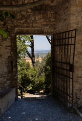 Medieval Castle gate with trees and tower of a Church at backside view, San Gimignano, Italy