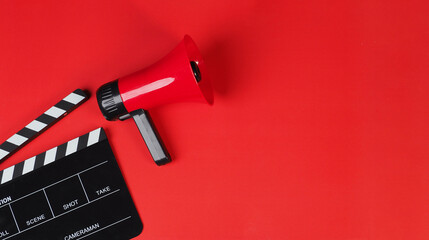 Clapper board and red megaphone on red background.