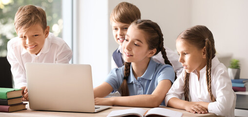 Fototapeta premium Cute little pupils with laptop in classroom