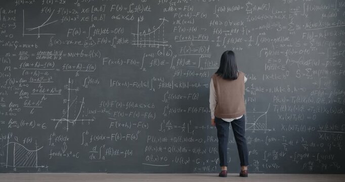 Back view of Asian woman scientist walking to chalkboard and writing formula focused on mathematics in research center. Science and education concept.