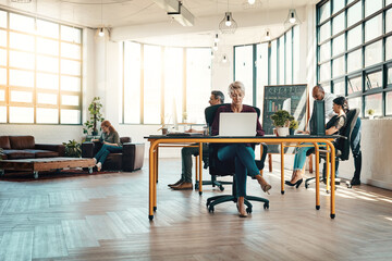 Coworking space, desk and laptop with business people in modern office for creative job or occupation. Computer, design and company with employee group in startup workplace for development or growth