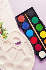 A white plastic palette with a watercolor palette with brush and a picture. Leisure activities and hobby theme