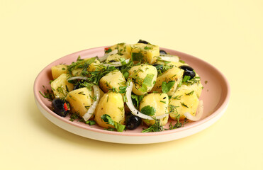 Plate of tasty Potato Salad with vegetables on yellow background