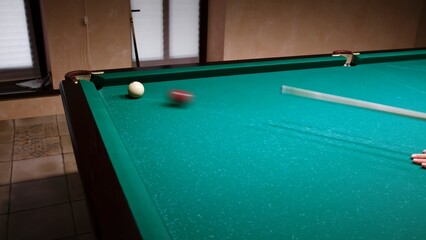 Russian billiards on a green table. American billiard. The player hits the white ball with a cue and rolling a red ball into the pocket. Successful shot. Pastime at home playing sport game hobby