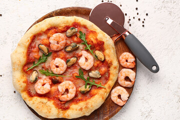 Plate with tasty seafood pizza and cutter on light background