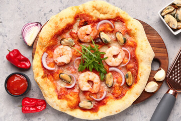 Wooden board with tasty seafood pizza on grunge background