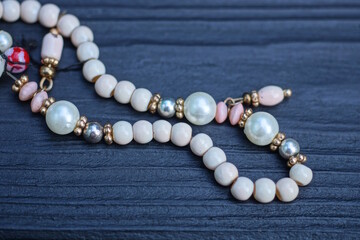 part of a necklace of white pearls lies on a black wooden table