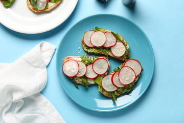 Plate with delicious radish bruschettas on blue background