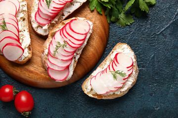 Board with delicious radish bruschettas and vegetables on black table